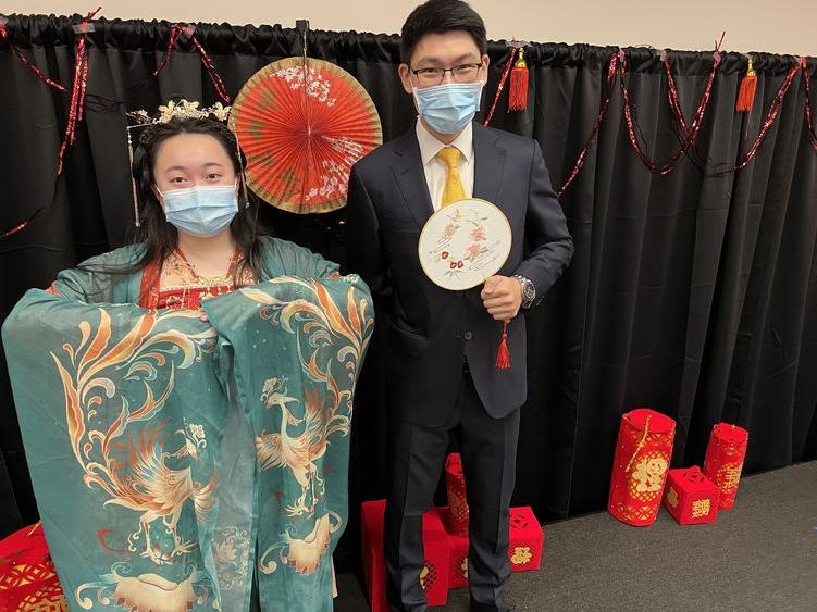 A male student wearing a suit and a female student wearing traditional Chinese clothing.